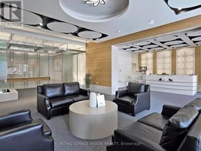 Toronto (Bendale) condo for rent - A modern living room with black leather furniture and a glass wall.