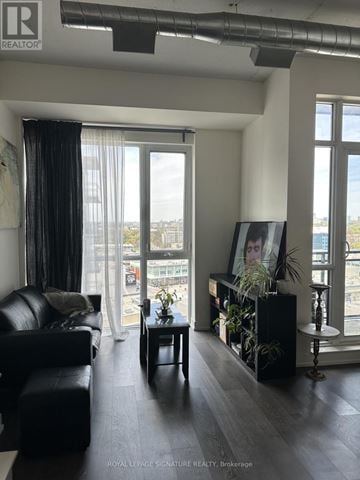 Toronto (Banbury-Don Mills) condo for rent - A living room with a black couch and a framed picture of a woman's face on the wall.
