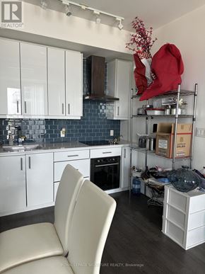 Toronto (Banbury-Don Mills) condo for rent - A kitchen with white cabinets and a black countertop.