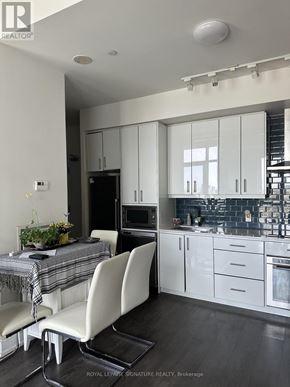 Toronto (Banbury-Don Mills) condo for rent - A modern kitchen with white cabinets and a dining table with a plaid tablecloth.