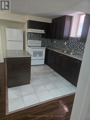 Brampton (Bram East) apartment for rent - A kitchen with black cabinets and a white fridge.