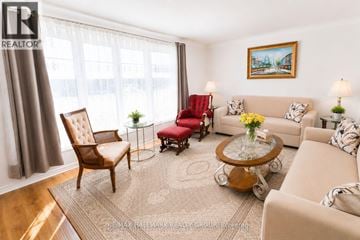 Ottawa townhouse for rent - A living room with a brown chair, a red chair, a beige couch, and a painting on the wall.