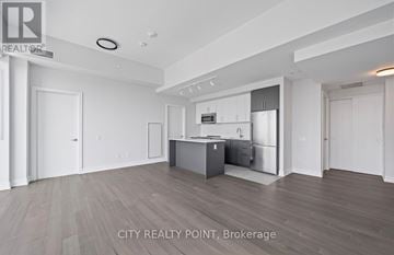 Toronto (University) condo for rent - A spacious kitchen with white cabinets and a wooden floor.