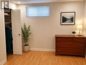 London South (South U) apartment for rent - A room with a wooden floor, a white door, a dresser, a potted plant, and a framed picture on the wall.