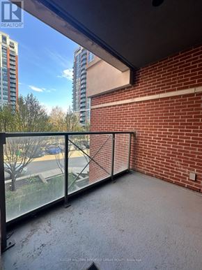 Markham (Unionville) condo for rent - A balcony with a glass railing overlooking a parking lot and buildings.