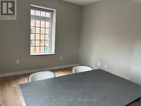 Oshawa (Central) condo for rent - A room with a grey table and two chairs with a window showing a building outside.
