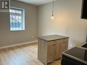 Oshawa (Central) condo for rent - A kitchen area with a wooden island and a window.