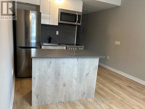Oshawa (Central) condo for rent - A kitchen with a stainless steel refrigerator and a wooden island.