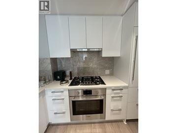 Vancouver townhouse for rent - A modern kitchen with white cabinets and stainless steel appliances.