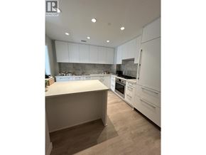 Vancouver townhouse for rent - A modern kitchen with white cabinets and a wooden floor.