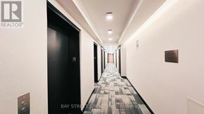 Toronto (Clanton Park) condo for rent - A long hallway with a carpeted floor and a black door on the left.