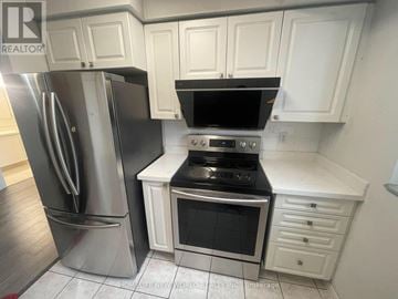 Toronto (Newtonbrook East) condo for rent - A kitchen with white cabinets and a black stove top oven.