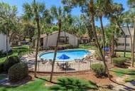 Gainesville apartment for rent - A pool surrounded by a fence and trees.