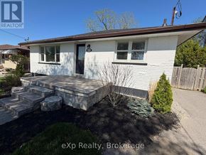 Oshawa (Eastdale) apartment for rent - A white house with a porch and a small garden in front.