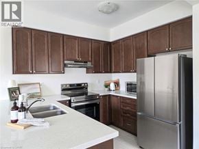 Ancaster townhouse for rent - A kitchen with brown cabinets and a stainless steel refrigerator.