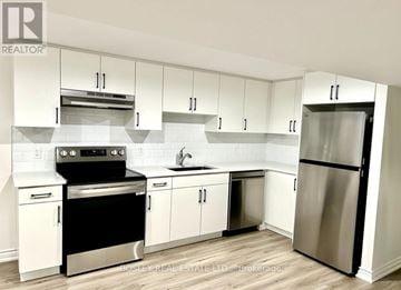 Niagara-On-The-Lake (Town) apartment for rent - A white kitchen with a stainless steel refrigerator and oven.