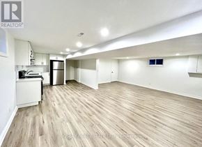Niagara-On-The-Lake (Town) apartment for rent - A spacious room with wooden flooring and a kitchen area with white cabinets.