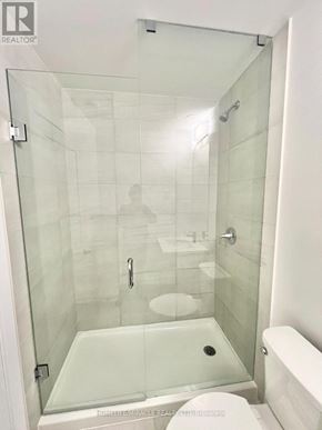 Kitchener townhouse for rent - A glass shower stall with a white toilet and a white bathtub.