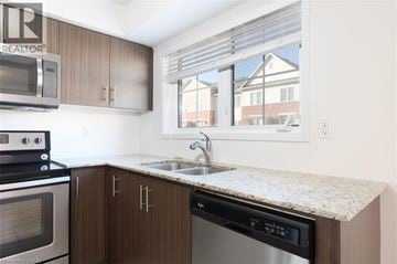 Oakville townhouse for rent - A kitchen with brown cabinets and a granite countertop.
