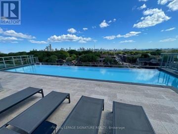 Toronto (Casa Loma) condo for rent - A pool with loungers and a view of the city in the distance.