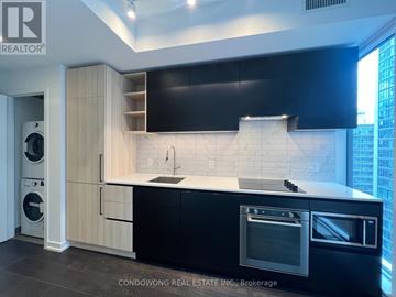 Toronto (Waterfront Communities) condo for rent - A modern kitchen with black countertops and a large window.