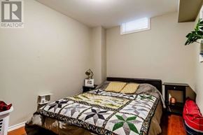 Whitby (Blue Grass Meadows) apartment for rent - A bedroom with a bed, a small table with a lamp and a plant on it, and a window with blinds.