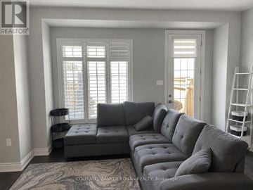New Tecumseth (Alliston) townhouse for rent - A grey sectional sofa in a living room with a ladder to the side.