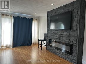 St. Catharines (Port Weller) apartment for rent - A modern living room with a stone fireplace and a flat screen TV mounted above it.