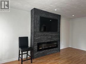 St. Catharines (Port Weller) apartment for rent - A black chair is placed in front of a stone fireplace.
