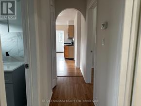 St. Catharines (Port Weller) apartment for rent - A hallway with a wooden floor and white walls leading to a kitchen.