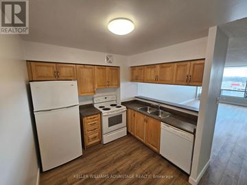 Brampton (Queen Street Corridor) condo for rent - A kitchen with wooden cabinets and white appliances.