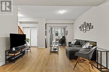 Hamilton (Stoney Creek Mountain) townhouse for rent - A living room with a black sofa and a television.