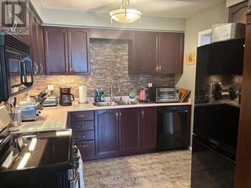 New Tecumseth (Tottenham) townhouse for rent - A kitchen with dark wood cabinets and a brick backsplash.