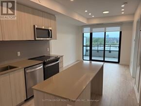 Milton (Cb Cobban) condo for rent - A kitchen with a microwave above the stove and a view of the city through the sliding glass doors.