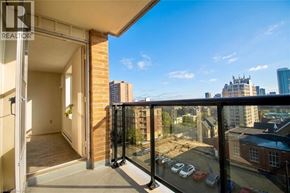 Kitchener condo for rent - A balcony with a glass railing overlooks a parking lot and buildings.