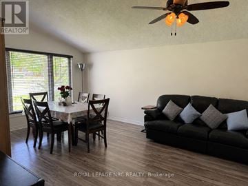 St. Catharines (Burleigh Hill) apartment for rent - A living room with a black couch, a dining table with chairs, and a ceiling fan.