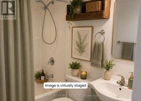 Oshawa (Central) apartment for rent - A bathroom with a white sink, a mirror, a plant, and a candle.