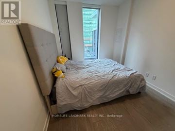 Toronto (Church-Yonge Corridor) condo for rent - A bedroom with a bed covered in a grey comforter and a yellow stuffed animal on the headboard.