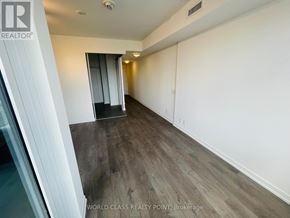 Toronto (South Parkdale) condo for rent - A room with a wooden floor and white walls.