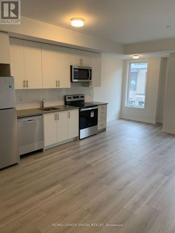 Mississauga (Erin Mills) townhouse for rent - A kitchen with white cabinets and a wooden floor.