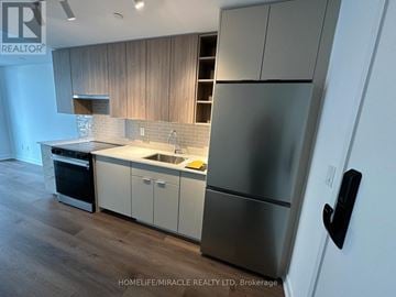 Burlington (Brant) condo for rent - A modern kitchen with a stainless steel refrigerator and white cabinets.
