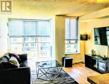 Toronto (Niagara) condo for rent - A living room with a black couch and a glass coffee table.