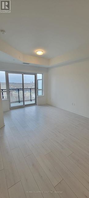Oakville (Go Glenorchy) condo for rent - A spacious room with a sliding glass door leading to a balcony.