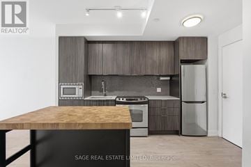 Toronto (Mimico) condo for rent - A modern kitchen with a wooden table and stainless steel appliances.