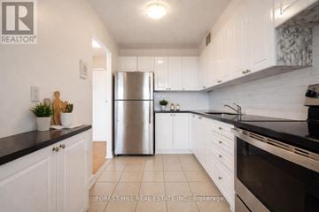 Toronto (York University Heights) house for rent - A kitchen with white cabinets and a stainless steel refrigerator.