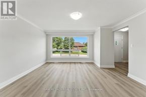 Oshawa (Lakeview) apartment for rent - A room with a large window showing a view of a house and trees.