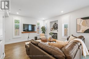 Burlington (Headon) townhouse for rent - A living room with a brown leather couch and a flat screen TV mounted on the wall.