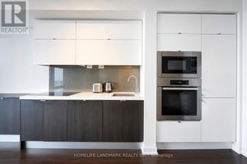 Toronto (Waterfront Communities) condo for rent - A modern kitchen with dark wood cabinets and white appliances.