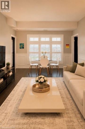 Kitchener condo for rent - A living room with a white couch, a coffee table with a bowl of flowers, and a large window with blinds.