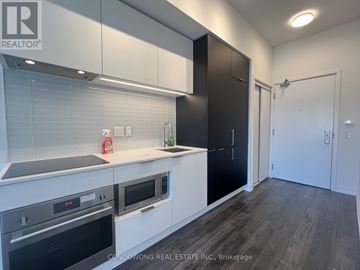 Toronto (Yonge-Eglinton) condo for rent - A modern kitchen with black and white cabinets and a wooden floor.
